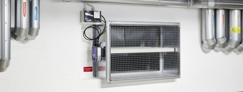 Brandschutzklappe mit elektrischem Stellantrieb, eingebaut im Lüftungskanal an einer Wand