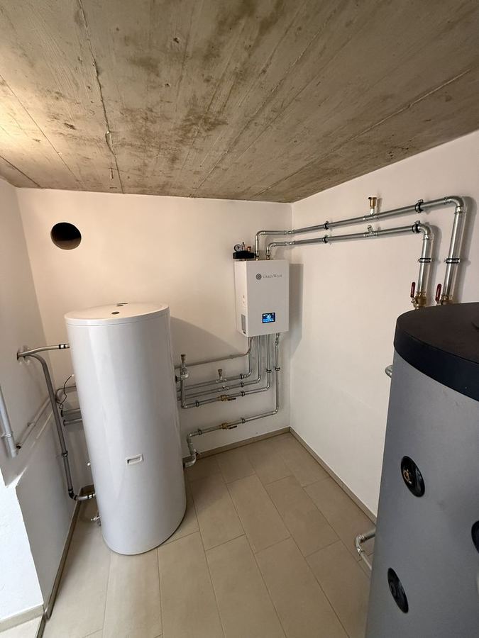 Technikraum mit Speicher, Pumpengruppe und isolierten Leitungen