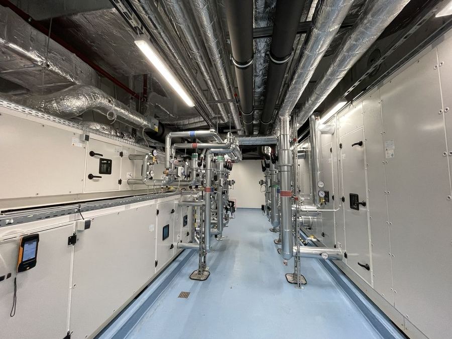 Technikzentrale mit mehreren Lüftungsgeräten nebeneinander und Kanalanbindung an der Decke