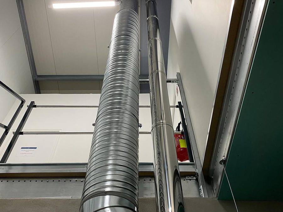 Edelstahlkamin und Abluftrohr, vertikal an der Wand bis zur Decke geführt